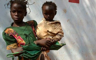 Girl carrying baby in front of the Zanga health centre22 by hdptcar CC BY 2.0 2 640x600 1